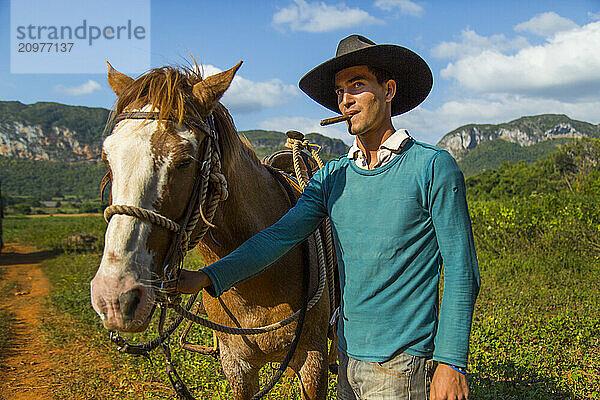 Young Cuban man posing with horse and cigar