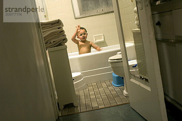 A boy plays in the bath tub.