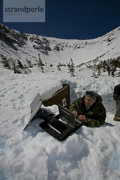 A member of the National Guard sets up a laptop with a satellite dish to transmit Inferno race times to the bottom of the course at Pinckham Notch.