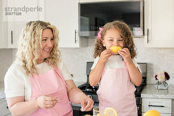 Little girl covering her mouth with lemon and mom watching