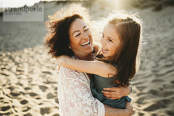 Grandma hugging kissing laughing beautiful grandchild girl at beach