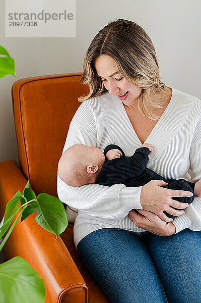 Mother cradles baby while sitting on leather chair.