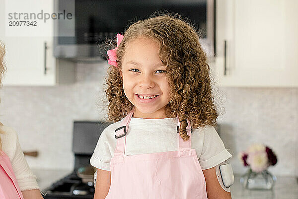 Close up of little girl with diabetes smiling in the kitchen