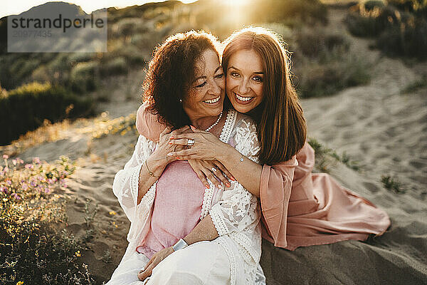 Stunning White woman hugging older mother smiling beach sunset Spain