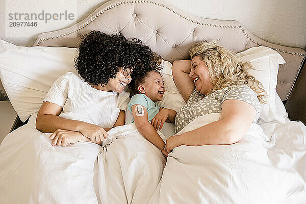 Mother and daughters in bed laughing together