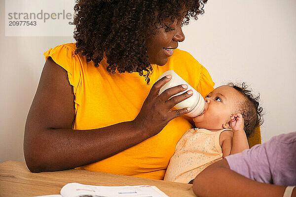 Loving mother feeding her baby with milk formula at home