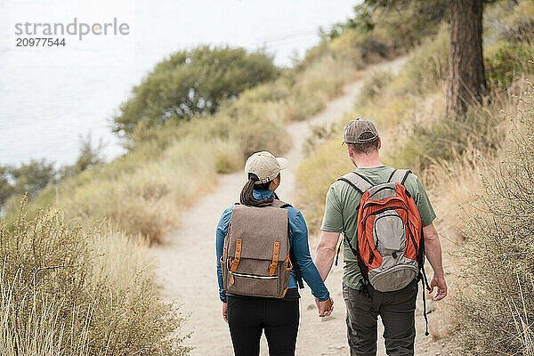 Couple hikers holding hands walking on a trail