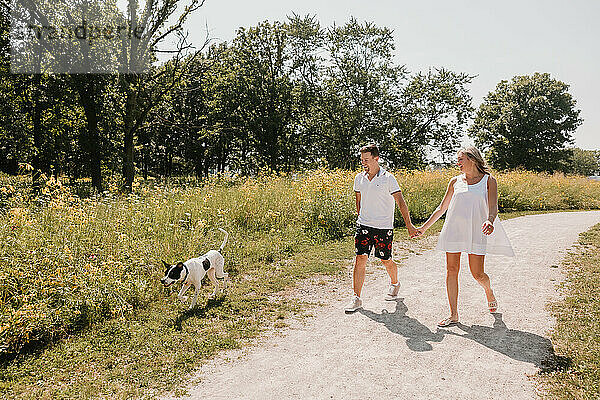 Young Couple walking with dog on path lined with wildflowers