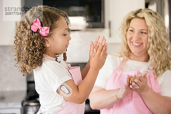 Girl with diabetes making cookie dough with mom smiling