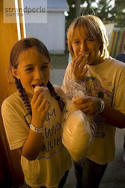 Two girls enjoy maple sugar cotton candy at the Fryeburg Fair in Maine.