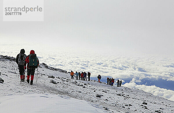 Climbing groups near the summit of Kilimanjaro  the highest mountain in Africa  between clouds layers.