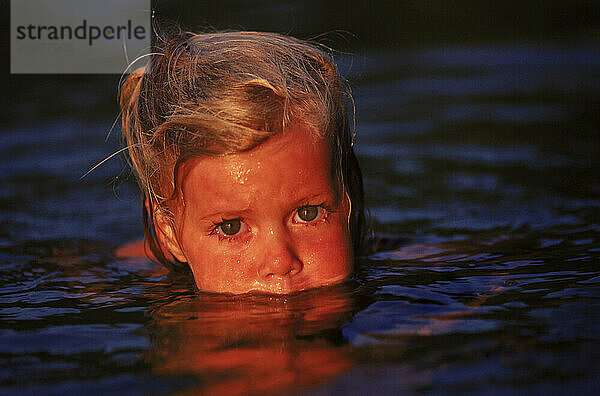 Close-up portrait of young girl swimming in Kezar Lake  Maine.