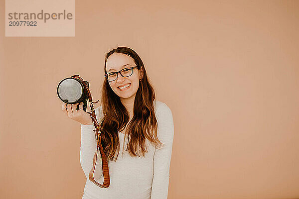 Smiling Hispanic female photographer holding camera