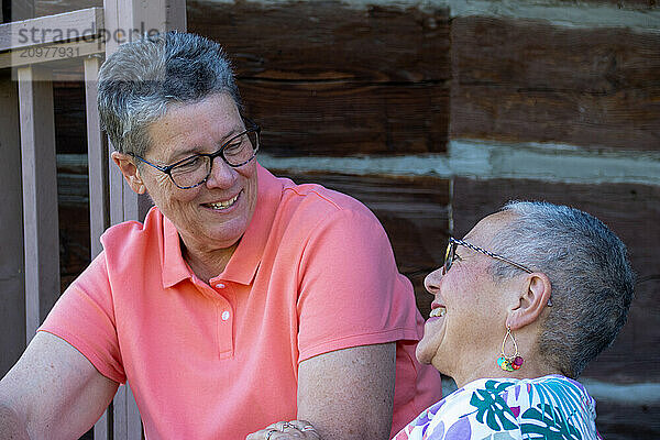 Older gay couple smiling and chatting on porch