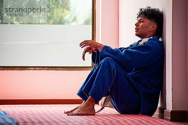 Judo fighter portrait resting in dojo with some trees at background