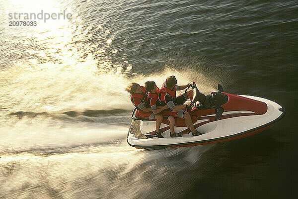 Aerial View a family racing across the lake on their jet ski at sunset.