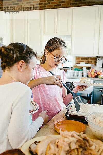 Girls get Thanksgiving food in kitchen at home with family