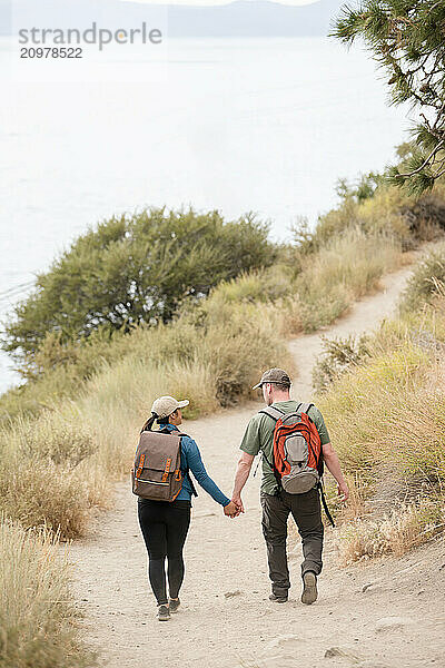 Couple hikers holding hands walking on a trail