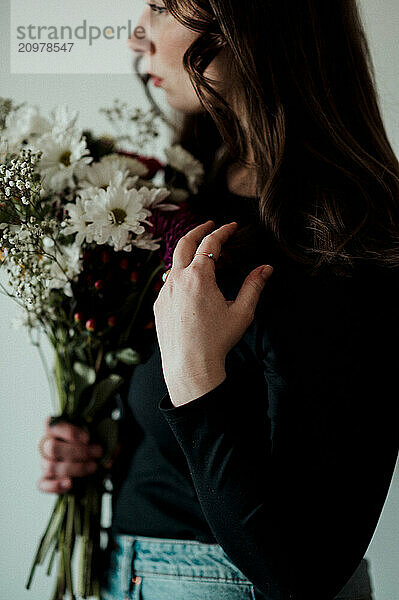 Woman holding a bouquet of flowers close to her face.