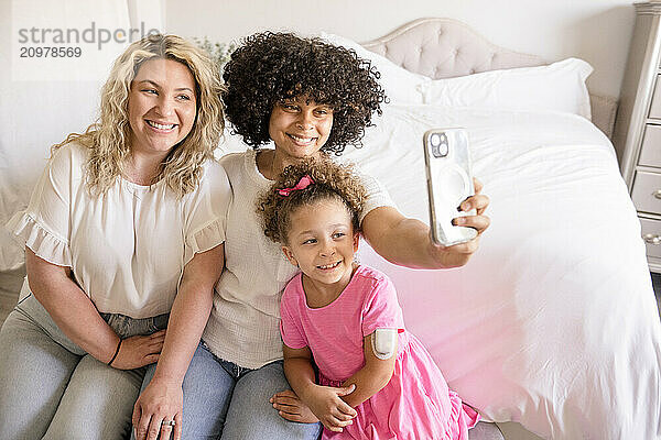 Mother and daughters are taking a selfie in the bedroom