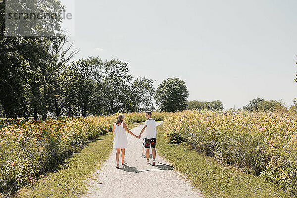 Couple walking with dog on path lined with wildflowers