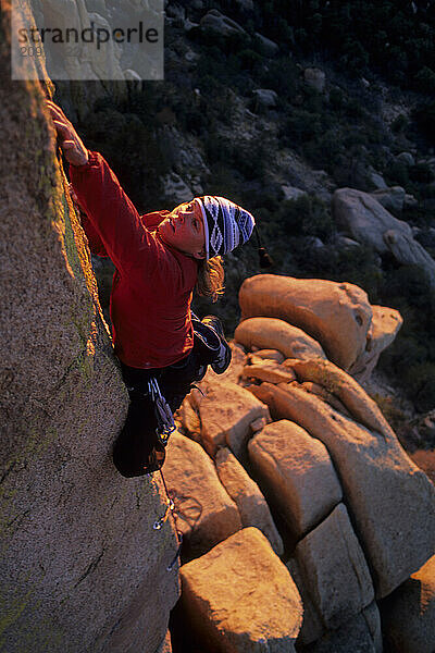 Woman rock climber reachies for small hold on granite arete  Cochise Strondhold  Arizona.