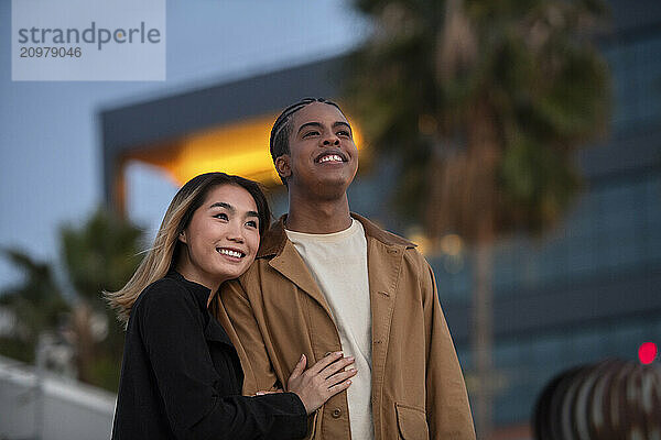 Asian woman embraces black african american male an urban roof-t