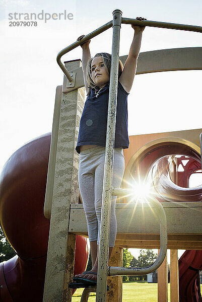 Young girl playing on playground equipment summer