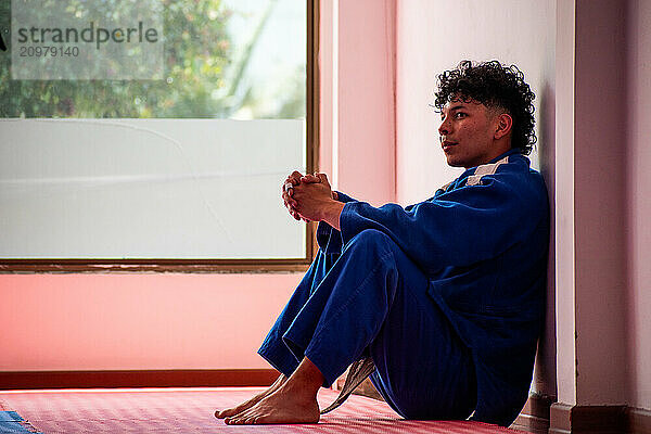 Judo fighter portrait resting in dojo with some trees at background