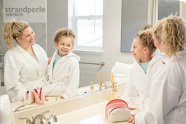 Mother and daughter is looking at their reflection in the bathroom