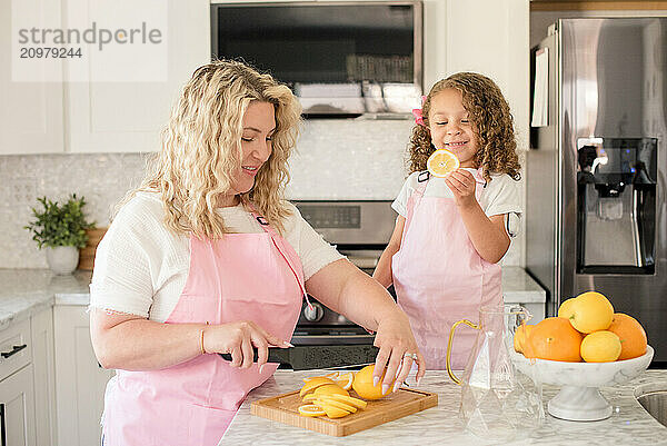 Mother cutting a lemon while daughter is holding a lemon slice