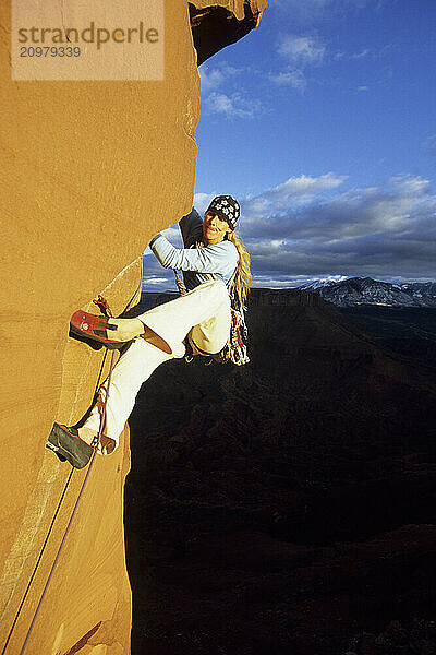 A woman rock climber moving up a sandstone tower in Castle Valley  Utah (blurred motion)