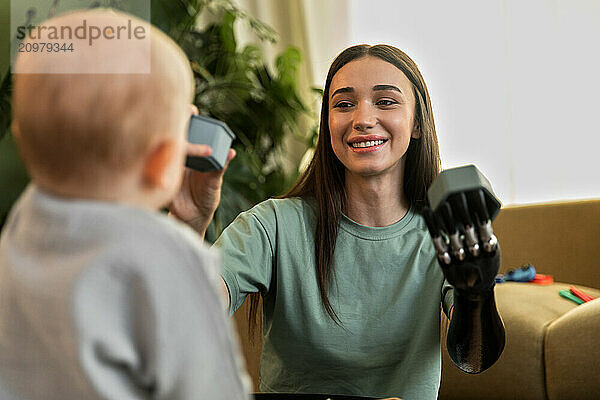 Young woman with prosthesis enjoys playing with baby