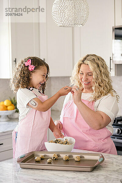 Daughter feeding mom some cookie dough in the kitchen