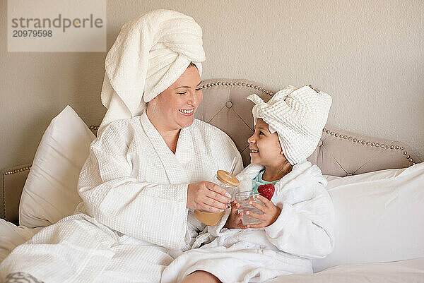 Mother and daughter smiling at each other wearing white robes