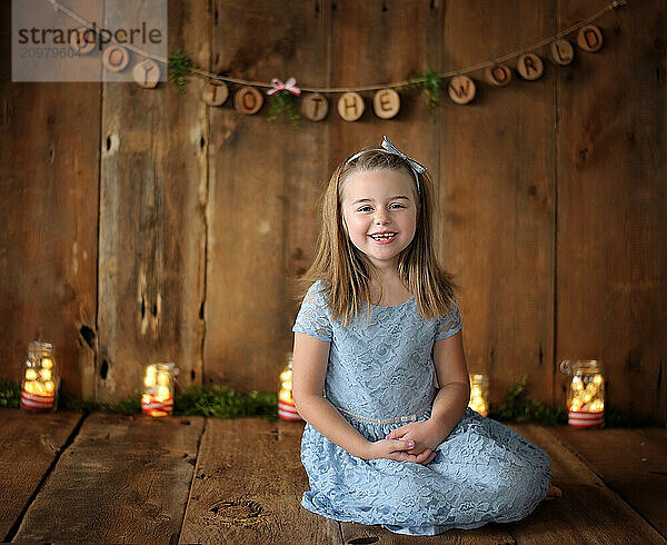 Beautiful young girl blue dress smiling wooden holiday backdrop