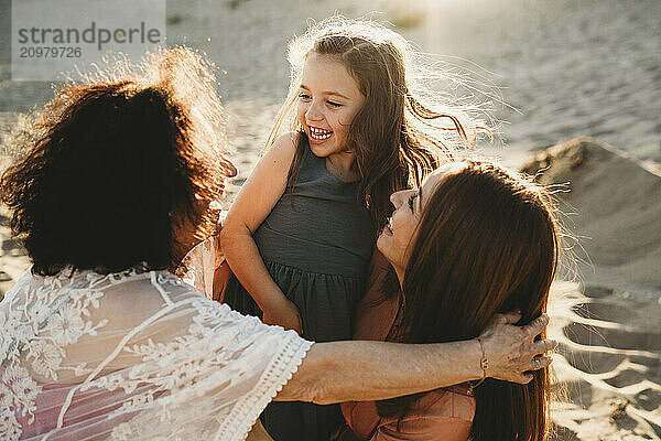 Happy girl smiling at grandmother and mom at the beach