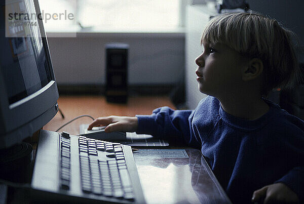 A young boy sits at his computer.