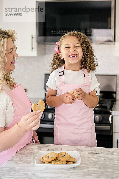 Biracial little girl laughing after she just bit into a cookie