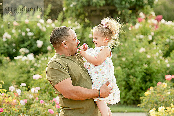 Father holding daughter laughing together in garden