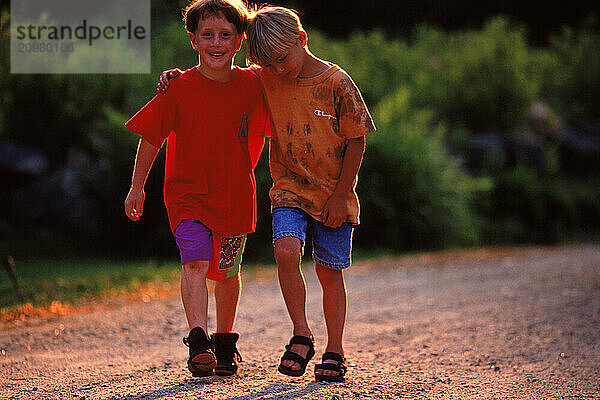 Two boys walk together down a country road in Maine.