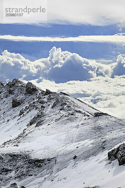 Climbers crossing the summit crater of Mt. Kilimanjaro  with storm clouds behind.