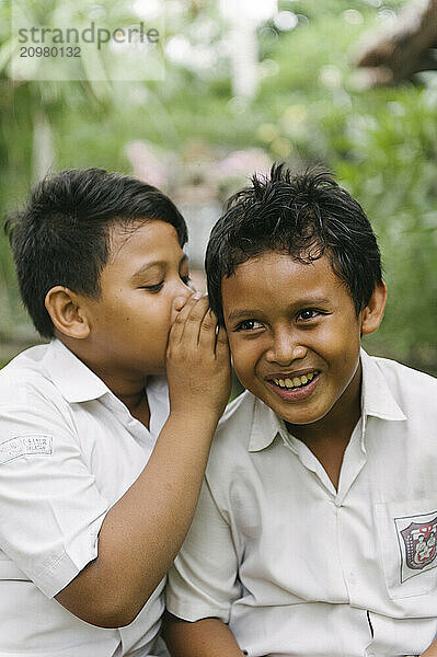 A group of young boys smiling and playing on an open field and climbing a tree