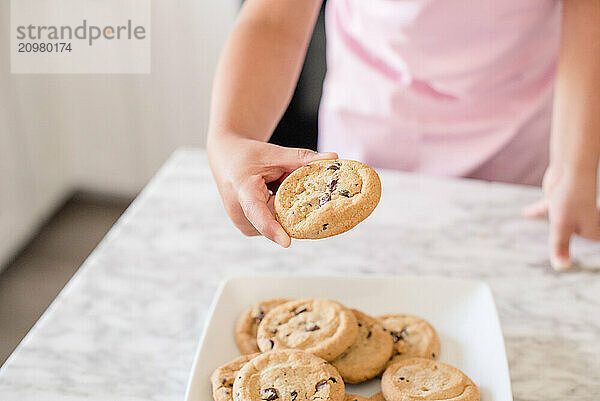 Close up of a little girls hands grabbing a chocolate chip cookie