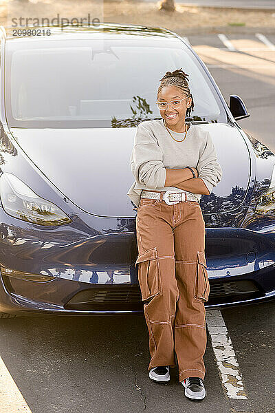 Young adult woman leaning against car