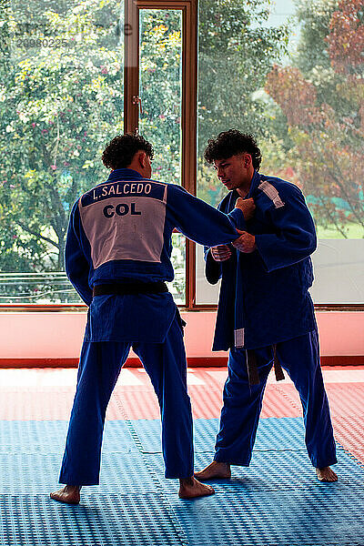 Two judo partners training in dojo with some trees outside