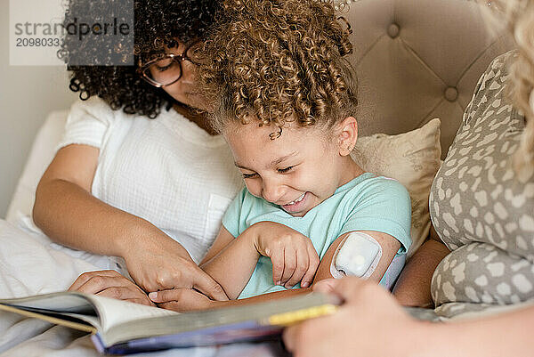 Little girl with glucose monitor being tickled by big sister