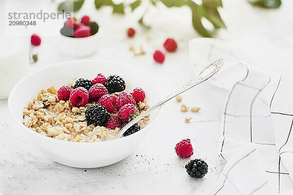 Morning healthy breakfast  white bowl full with granola  muesli  raspberry  blackberry on gray concrete table. Healthy eating  eco  bio food concept. Fresh tasty meal on grey background. Quality photo