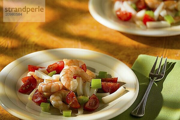 Shrimp salad with squid tomatoes and celery over an orange background