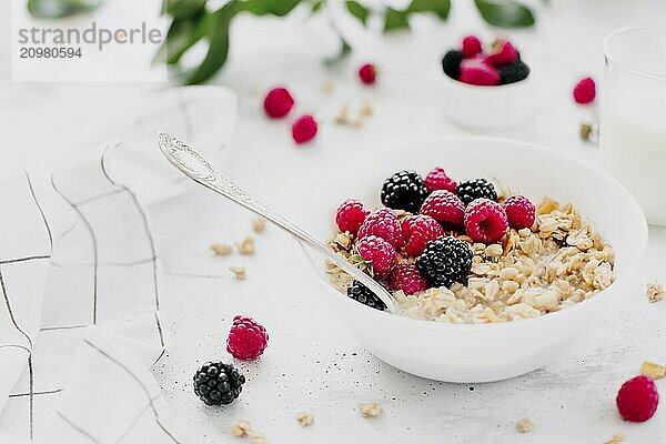 Morning healthy breakfast  white bowl full with granola  muesli  raspberry  blackberry on gray concrete table. Healthy eating  eco  bio food concept. Fresh tasty meal on grey background. Quality photo